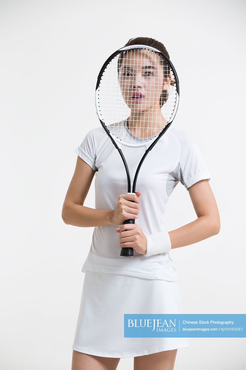 Young Chinese woman posing with tennis racket