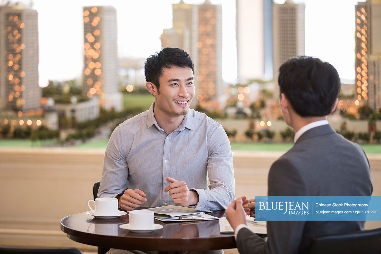 Happy young Chinese man buying new house from realtor