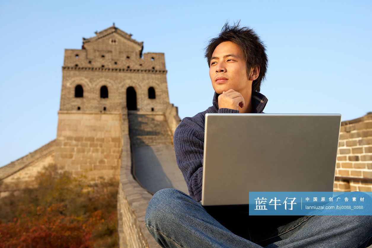 一位男孩正在长城上使用笔记本电脑
