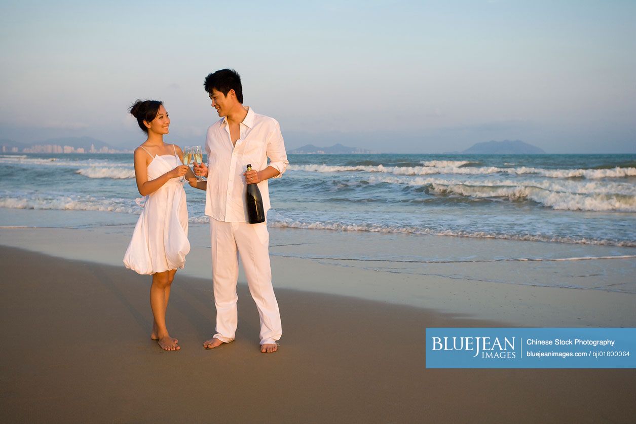 Young Chinese couple celebrating with a bottle of champagne