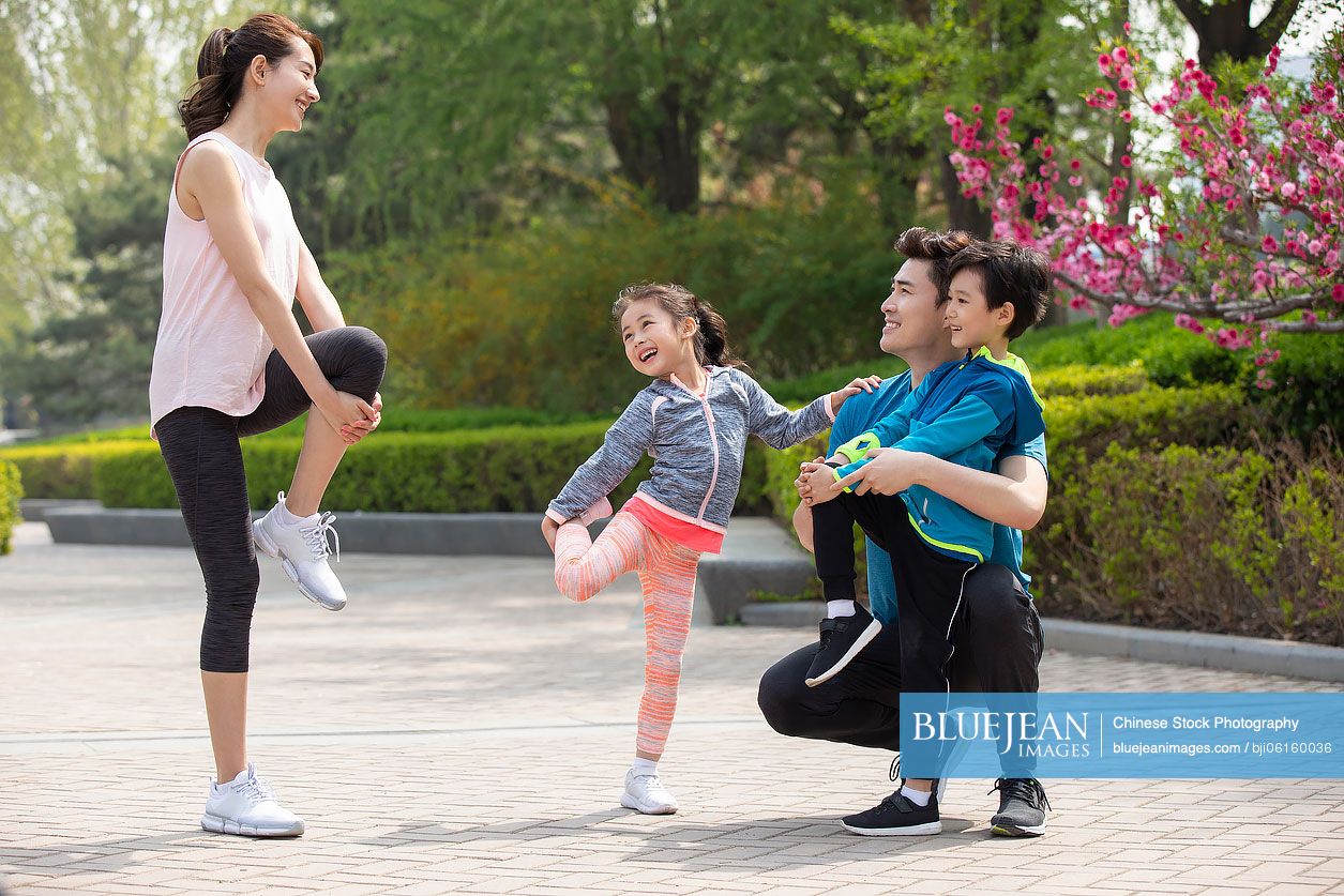 Happy young Chinese family exercising in park
