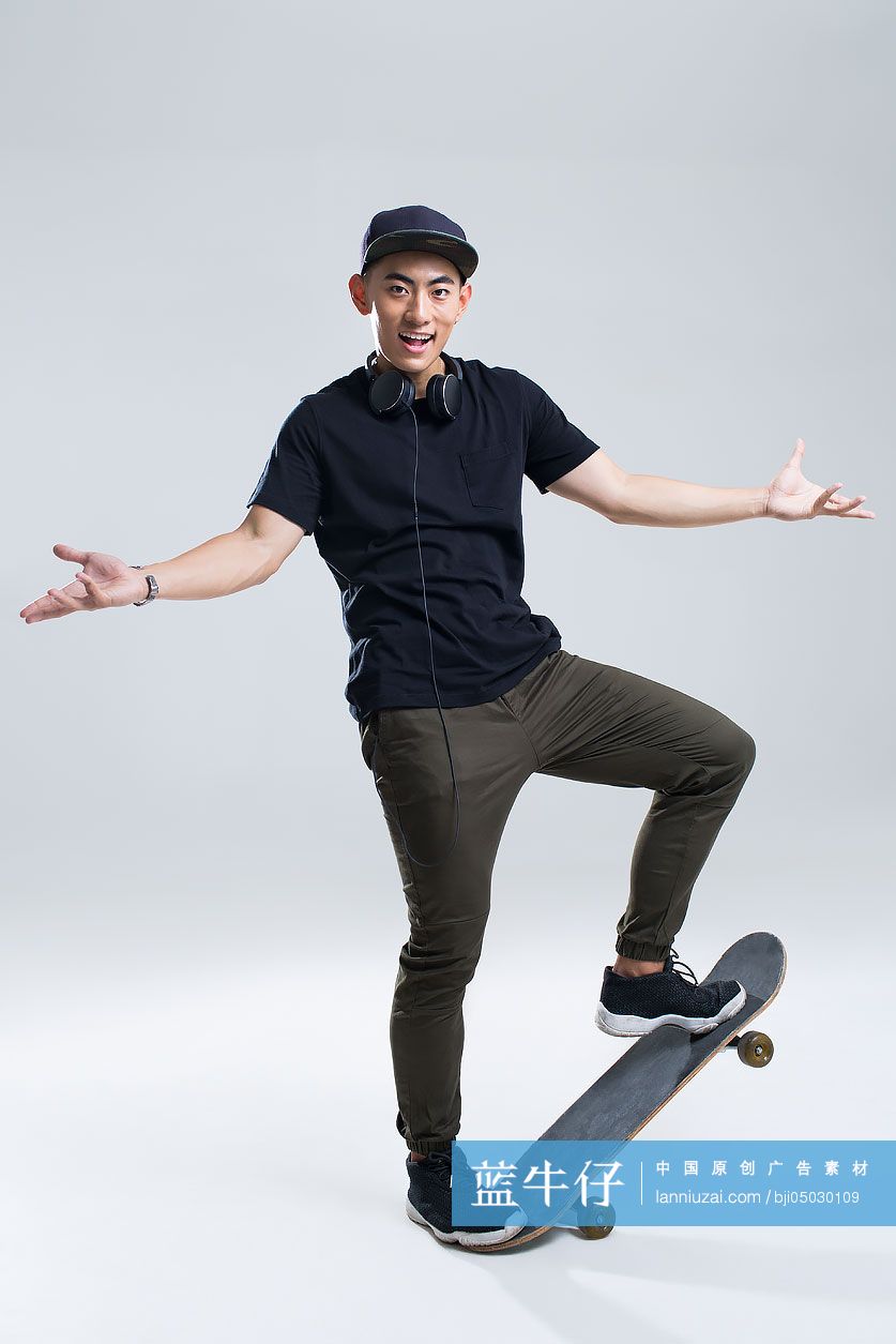 戴耳机的快乐年轻男子在滑滑板