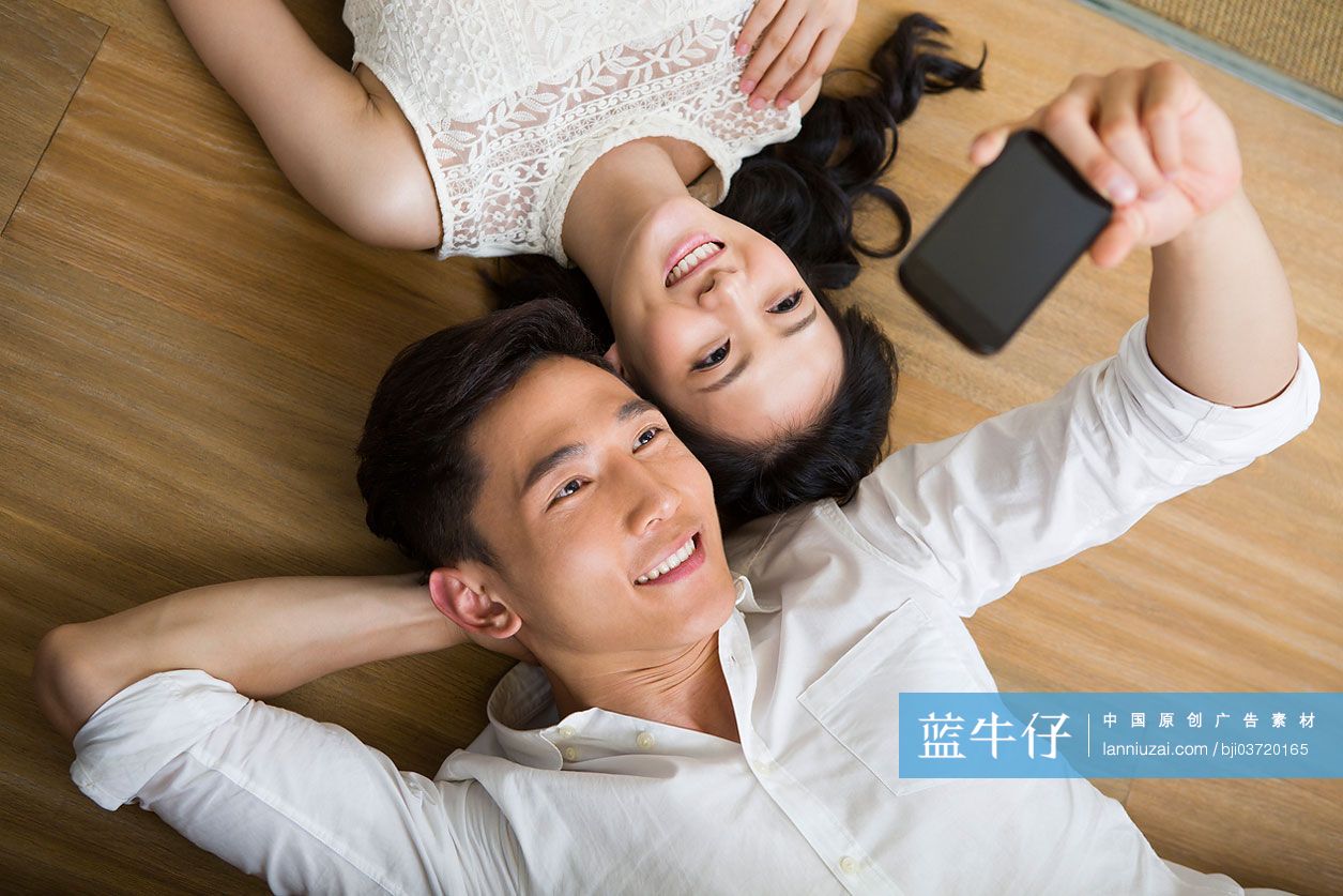情侣躺在地板上用手机自拍
