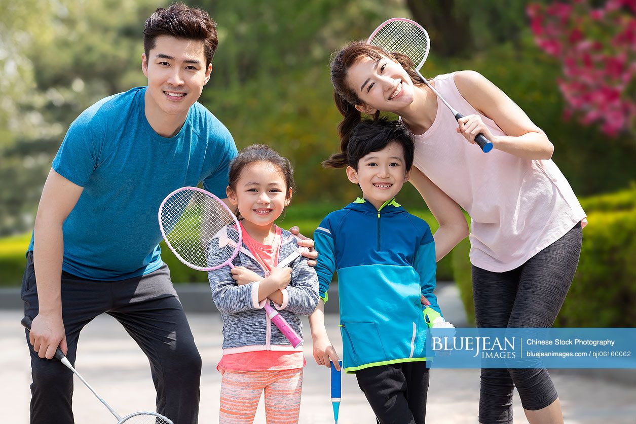 Happy young Chinese family playing badminton in park