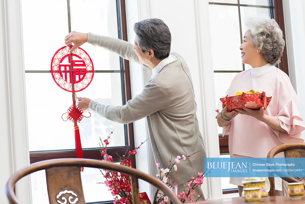 Senior couple decorating their house for Chinese New Year