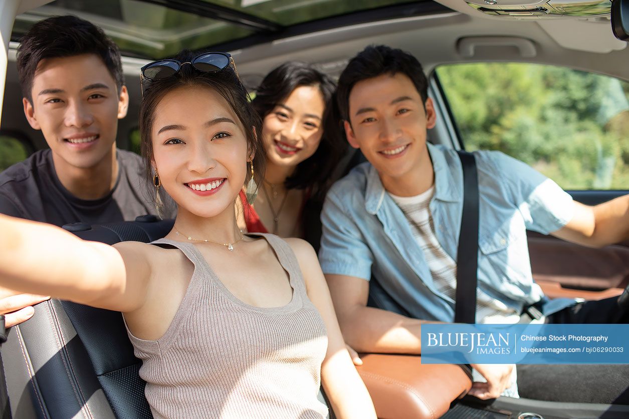 Happy young Chinese friends enjoying road trip