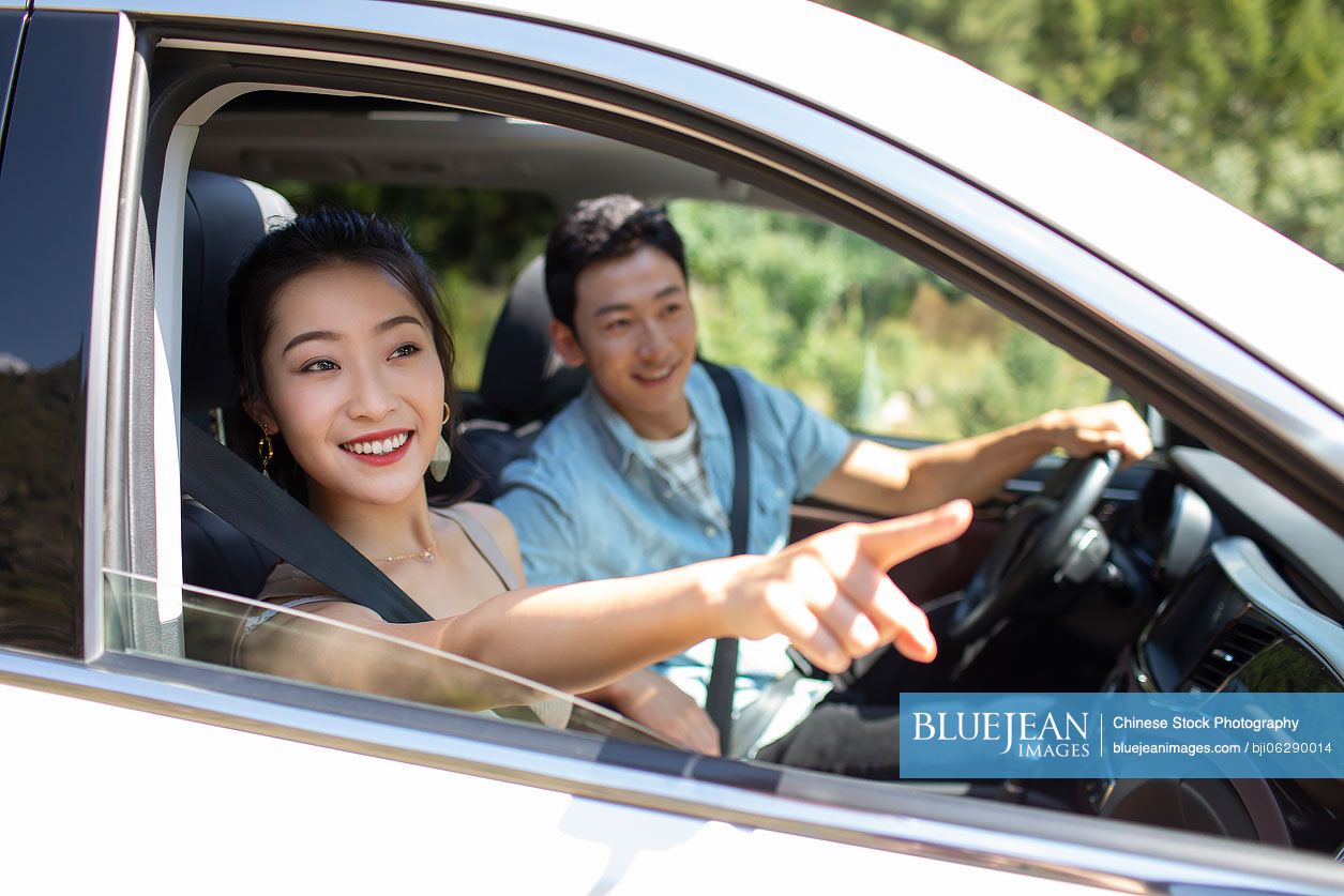 Happy young Chinese couple enjoying road trip
