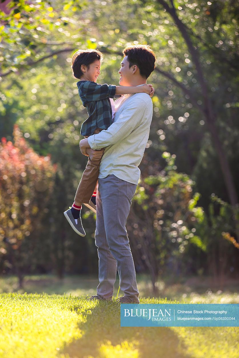 Happy Chinese father and son relaxing in park