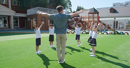 Foreign teacher and students exercising in kindergarten playground,4K