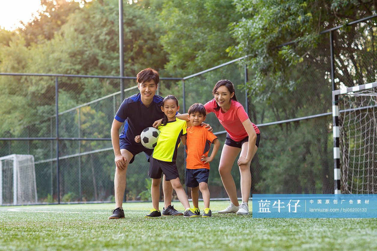 快乐的年轻家庭在足球场踢足球