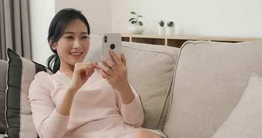 Happy young Chinese woman using smartphone in living room,4K