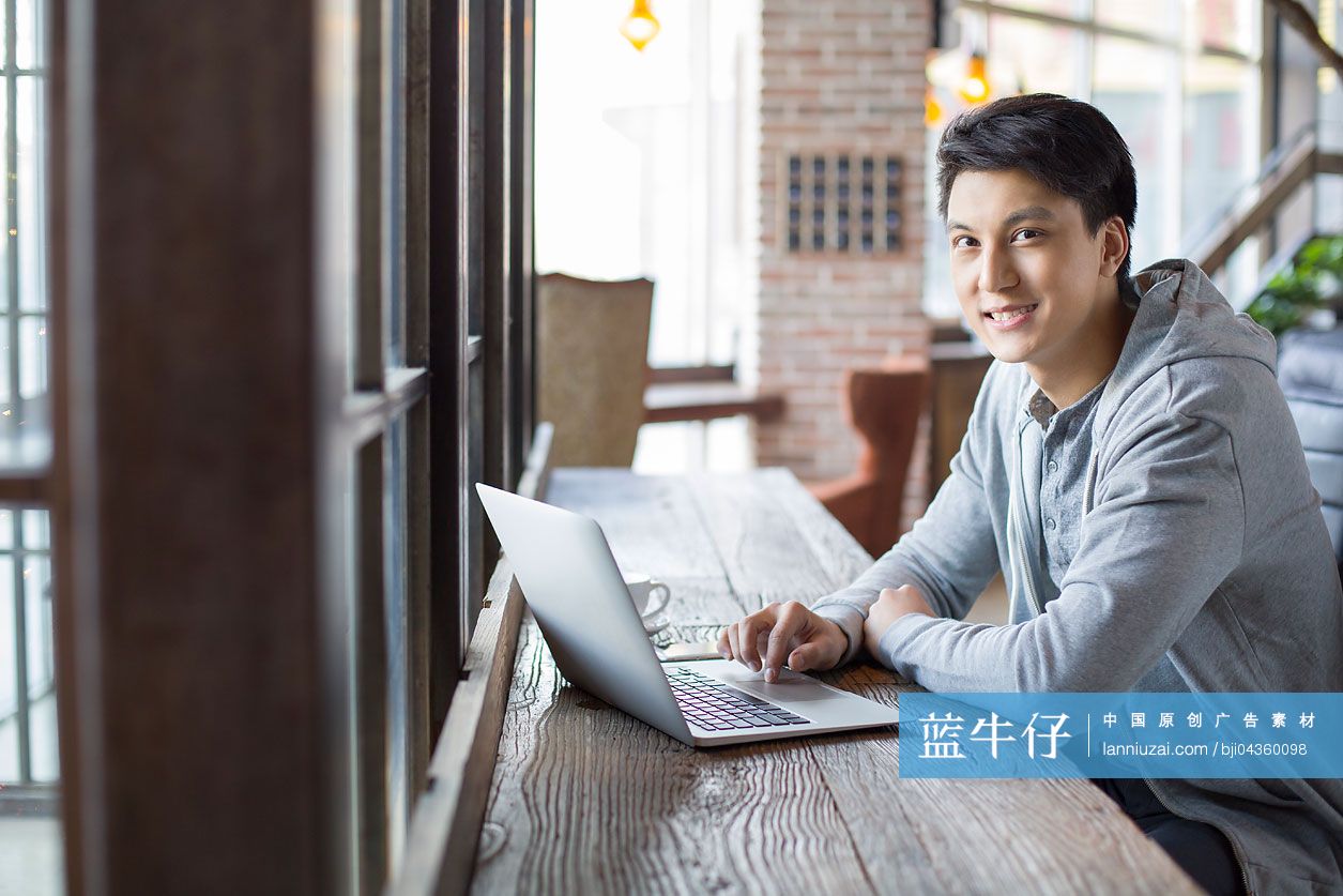 年轻男子在咖啡馆使用笔记本电脑