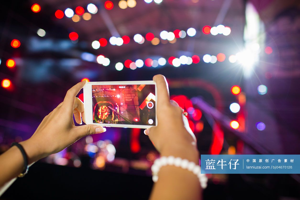 年轻女子在音乐节上用手机拍照