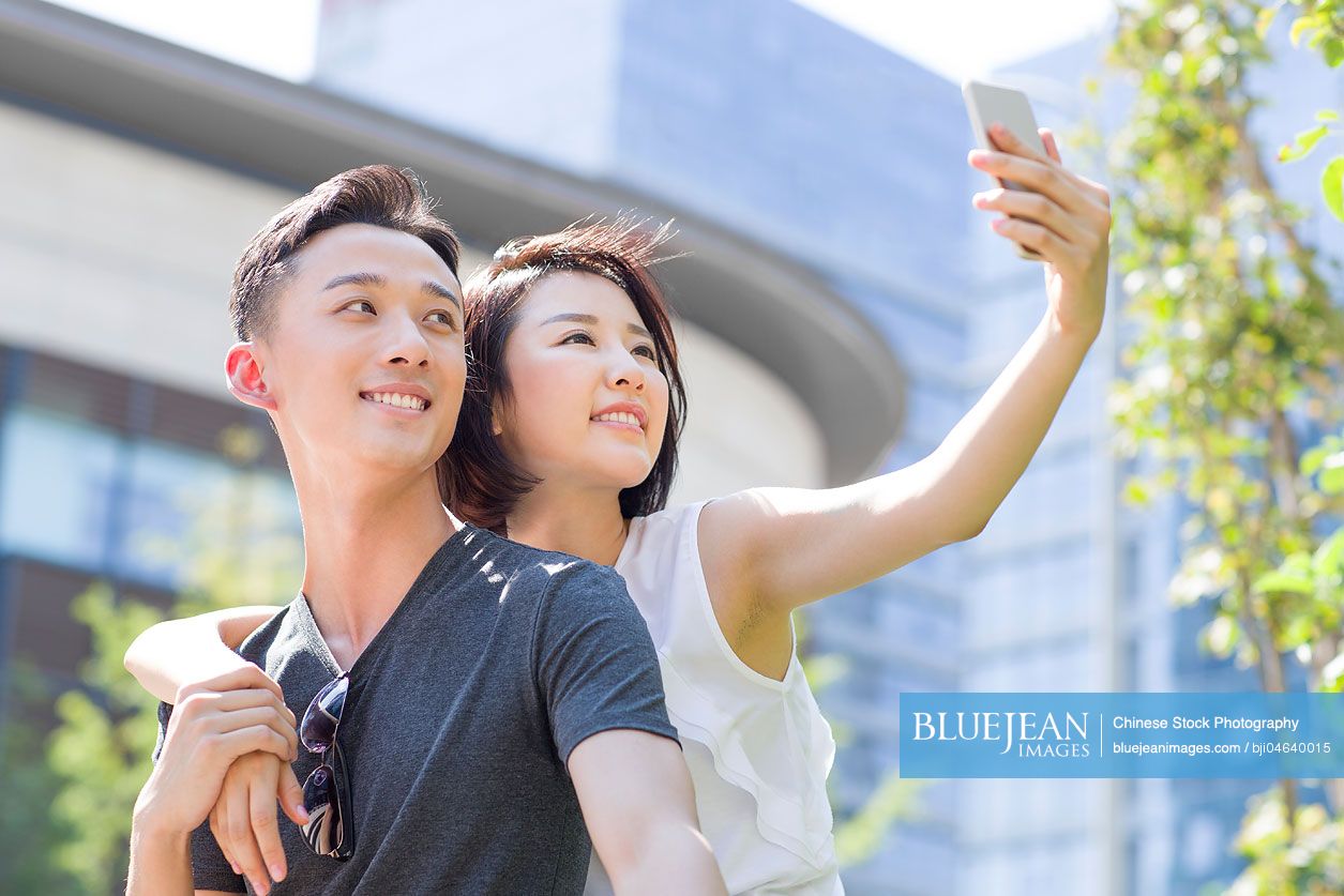 Happy young Chinese couple taking self portrait with a smart phone