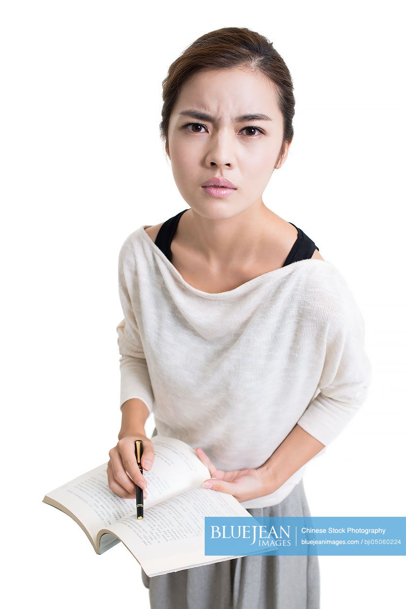 Angry young female Chinese teacher teaching with textbook