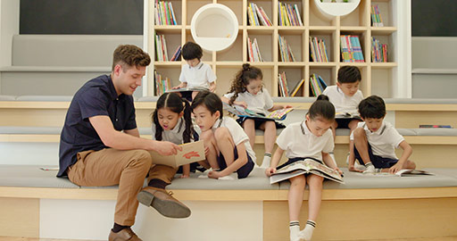 幼儿园外教和孩子们在图书馆看书