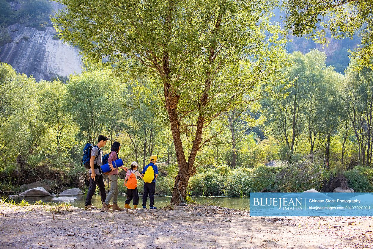 Happy young Chinese family hiking outdoors