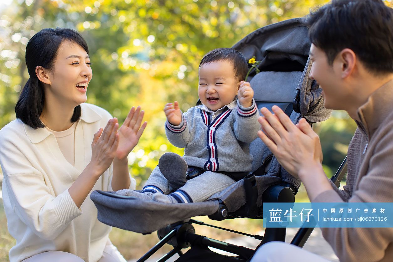 年轻父母在公园陪宝宝玩耍