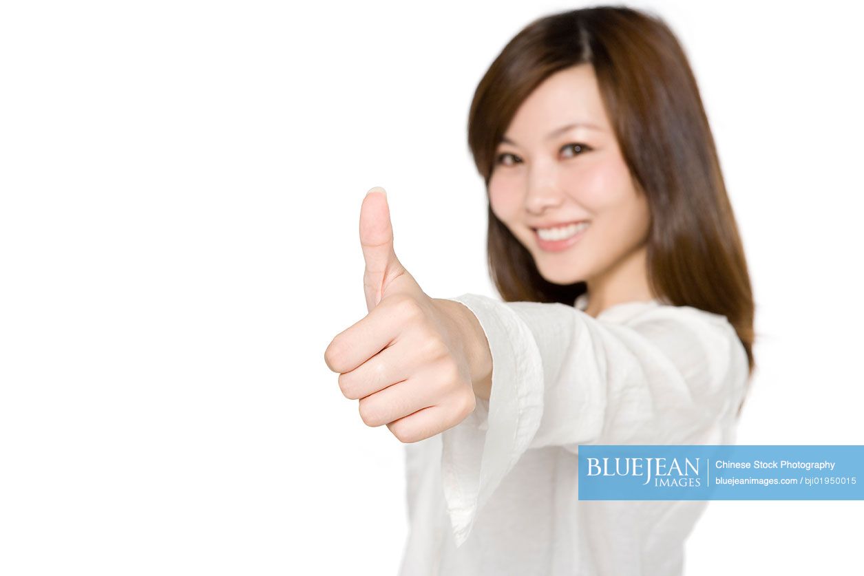 Portrait of young Chinese woman giving thumbs up