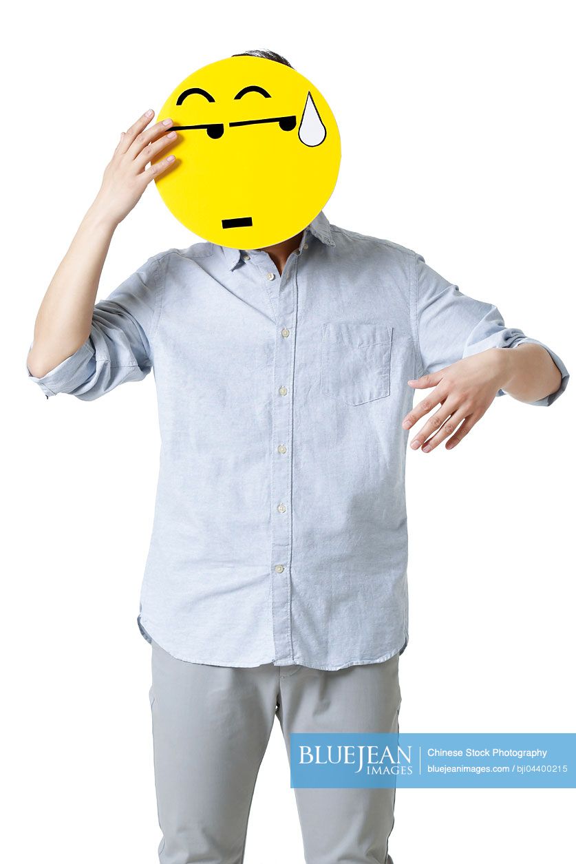 Young Chinese man with a embarrassed emoticon face in front of his face