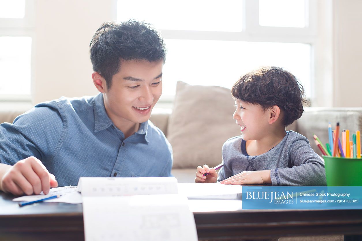 Young Chinese father helping son with homework