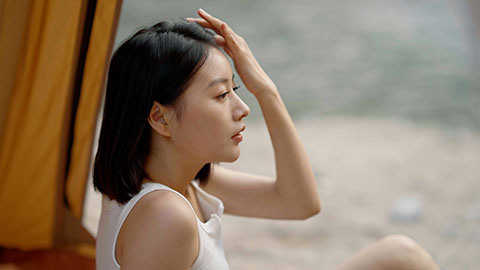 Cheerful young Chinese woman looking out from tent