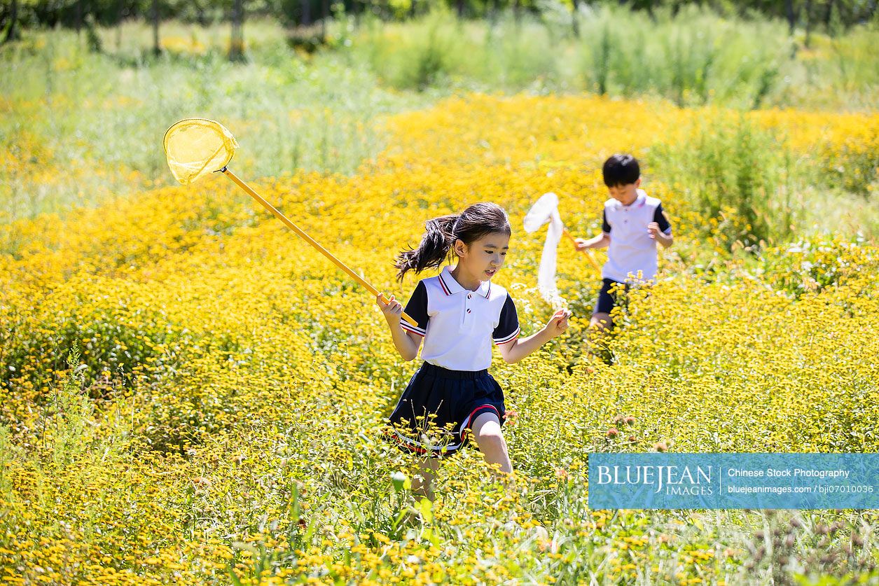 Cheerful Chinese school children relaxing in park