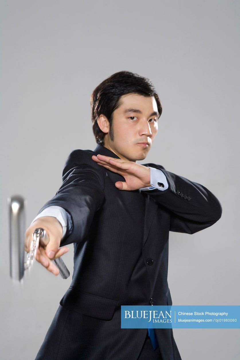Chinese businessman holding nunchukas on white background