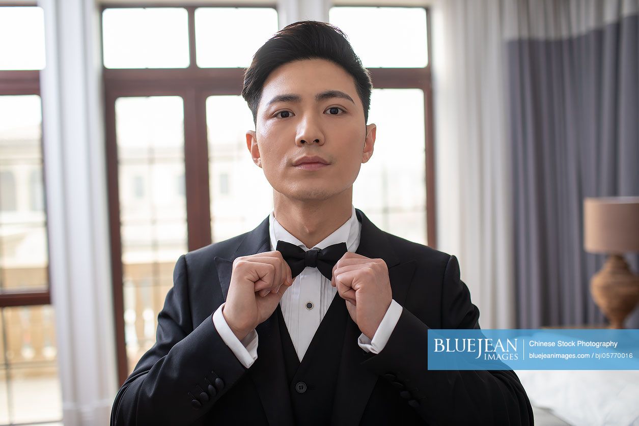 Young Chinese man getting dressed at home