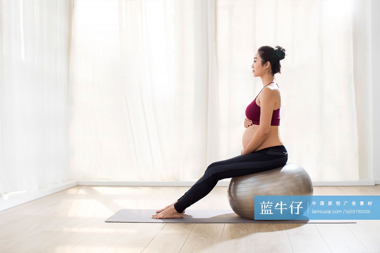 年轻孕妇坐在瑜伽球上