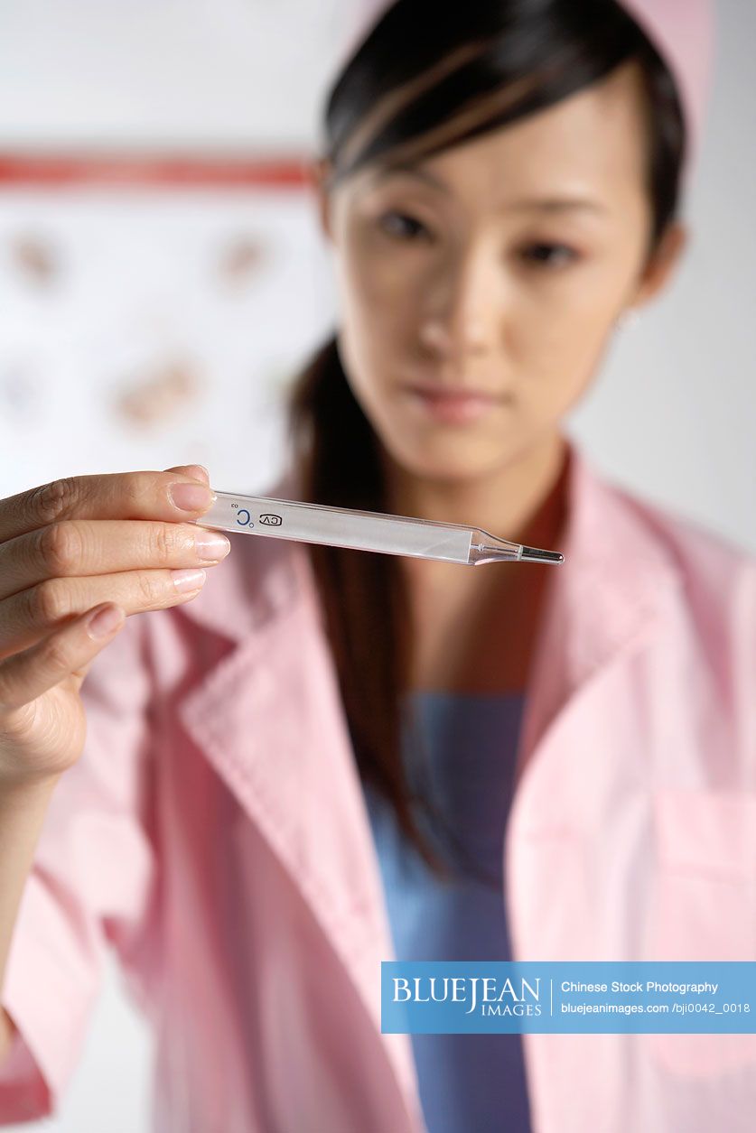 Chinese nurse holding a thermometer