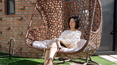 Happy young Chinese woman relaxing on hanging-chair,4K