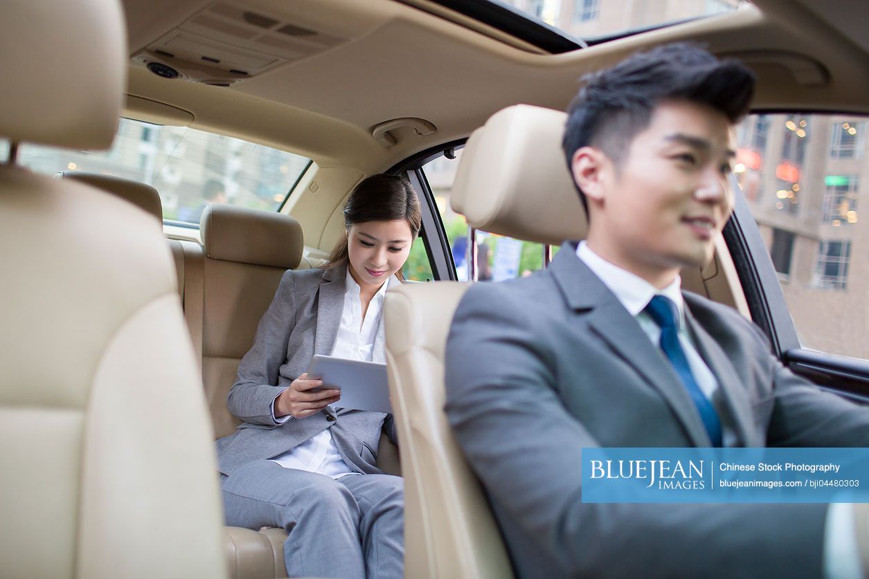 Chinese chauffeur driving car for a Chinese businesswoman