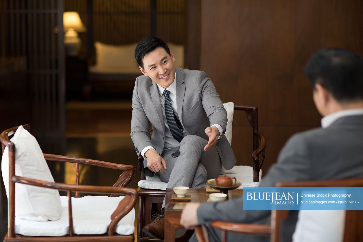 Cheerful Chinese businessmen talking in tea room