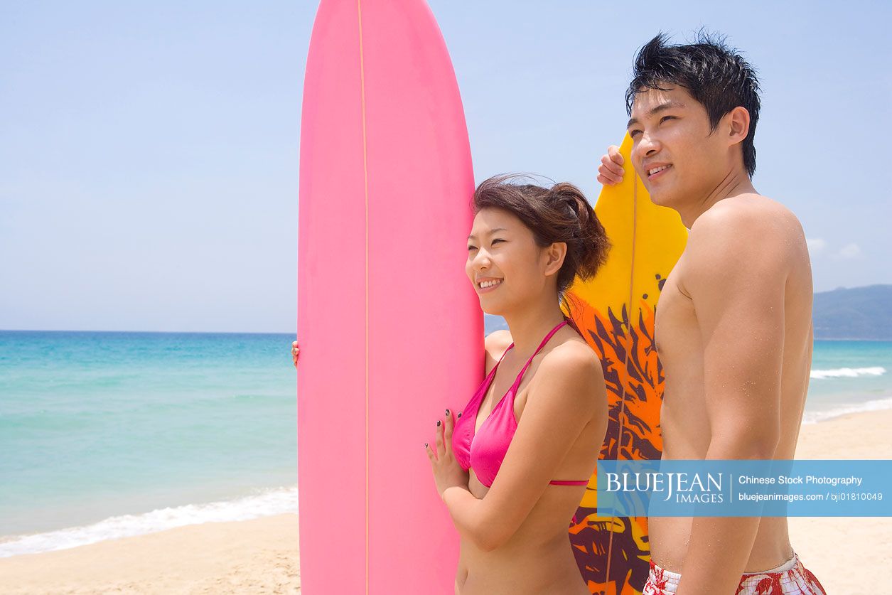 Young Chinese couple with a surfboard