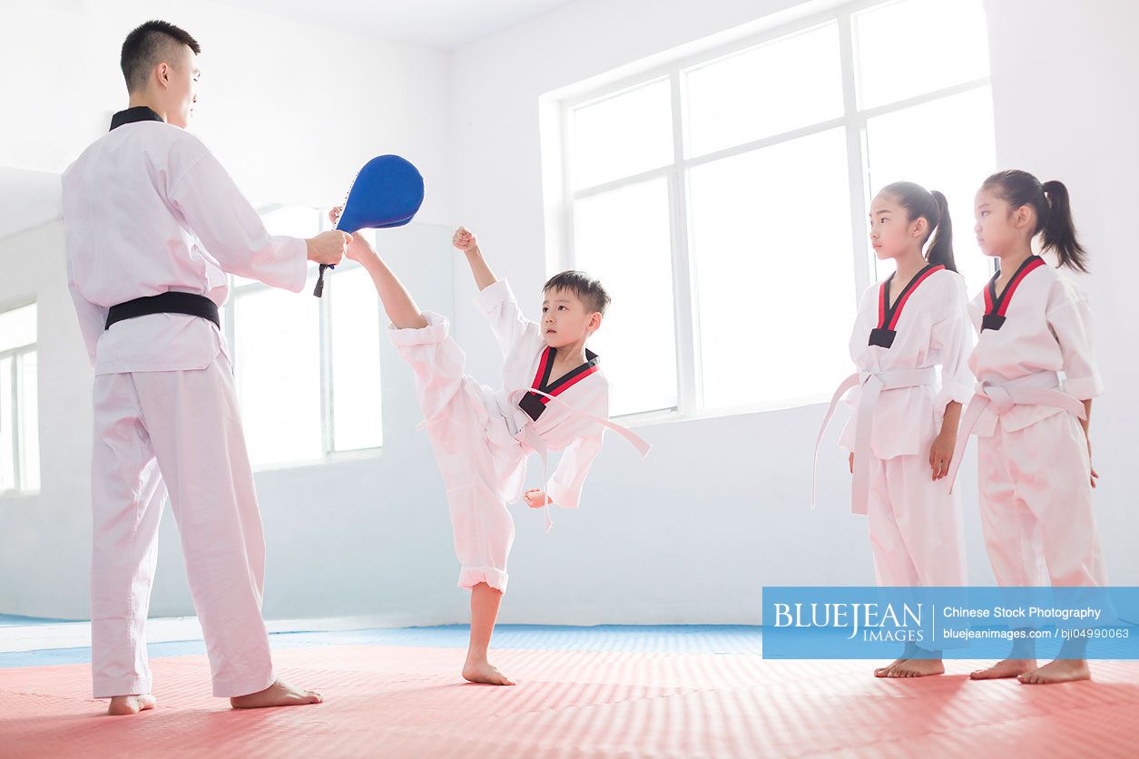 Young Chinese instructor teaching children Tae Kwon Do
