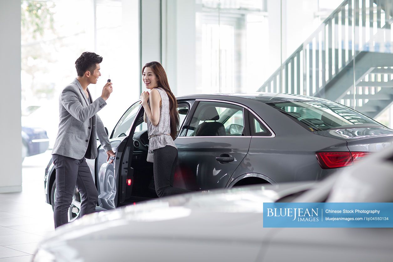 Young Chinese couple buying car in showroom