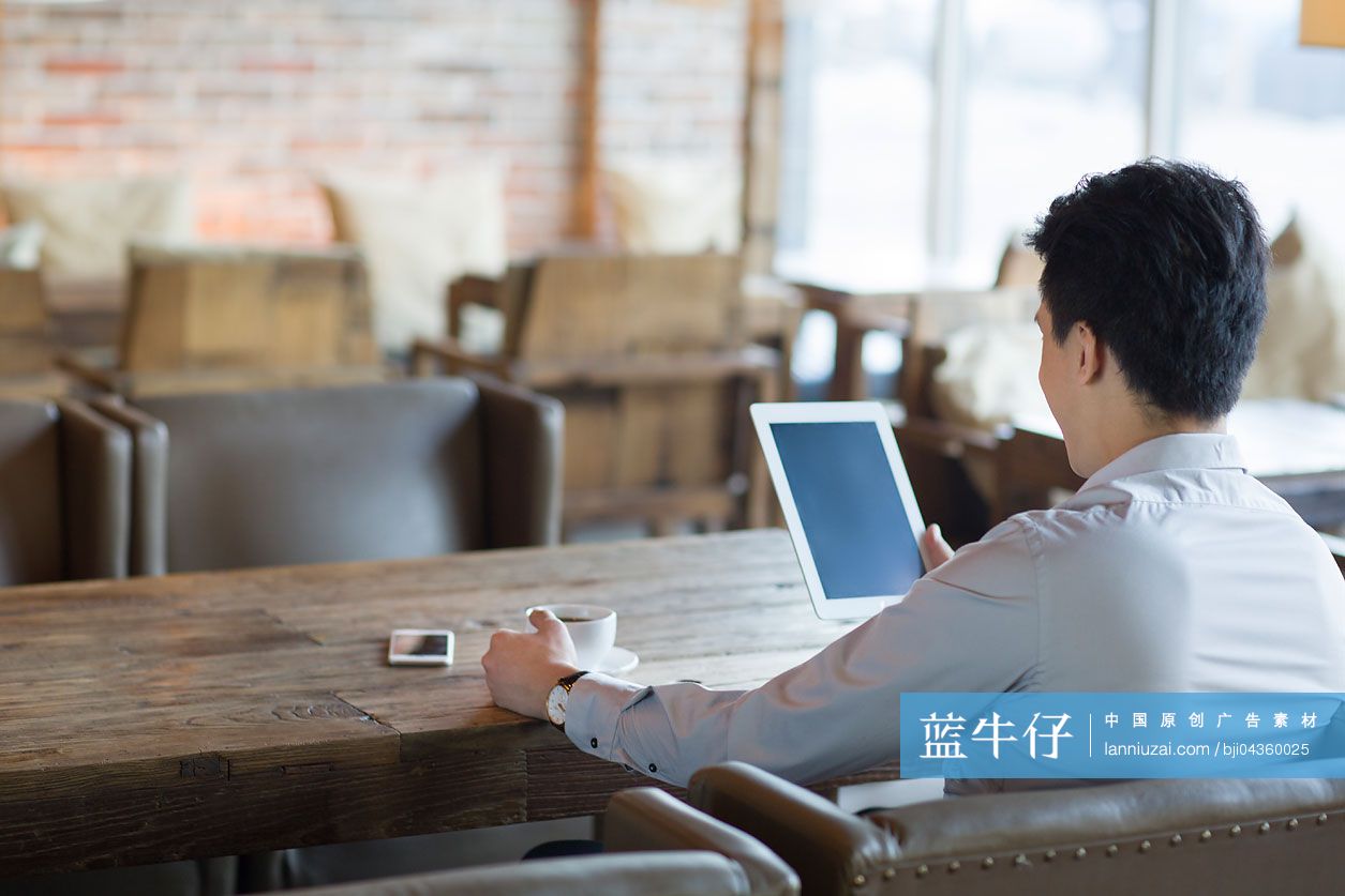 年轻男子在咖啡馆使用平板电脑