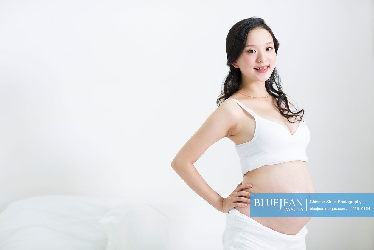 Happy pregnant Chinese woman with hand on hip-High-res stock photo for  download