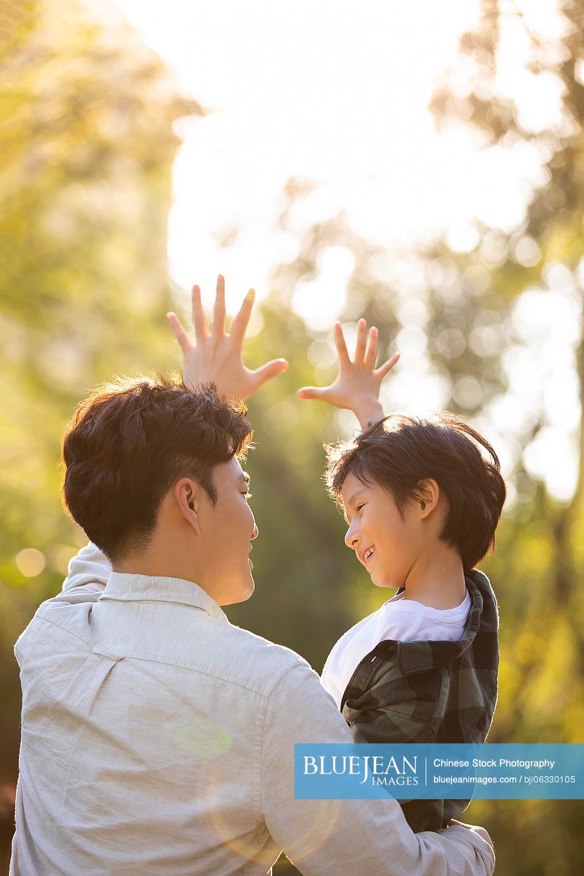 Happy Chinese father and son relaxing in park