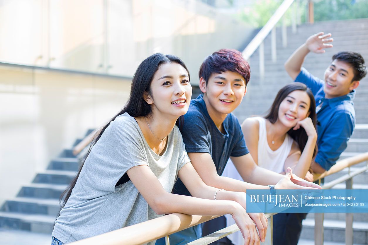 Happy young Chinese woman standing together with her friends