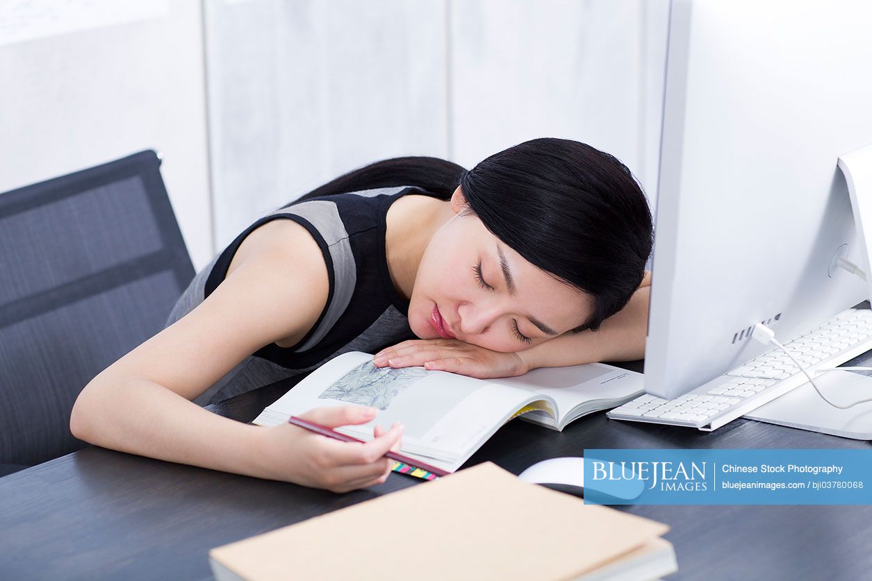 Young Chinese woman sleeping in office