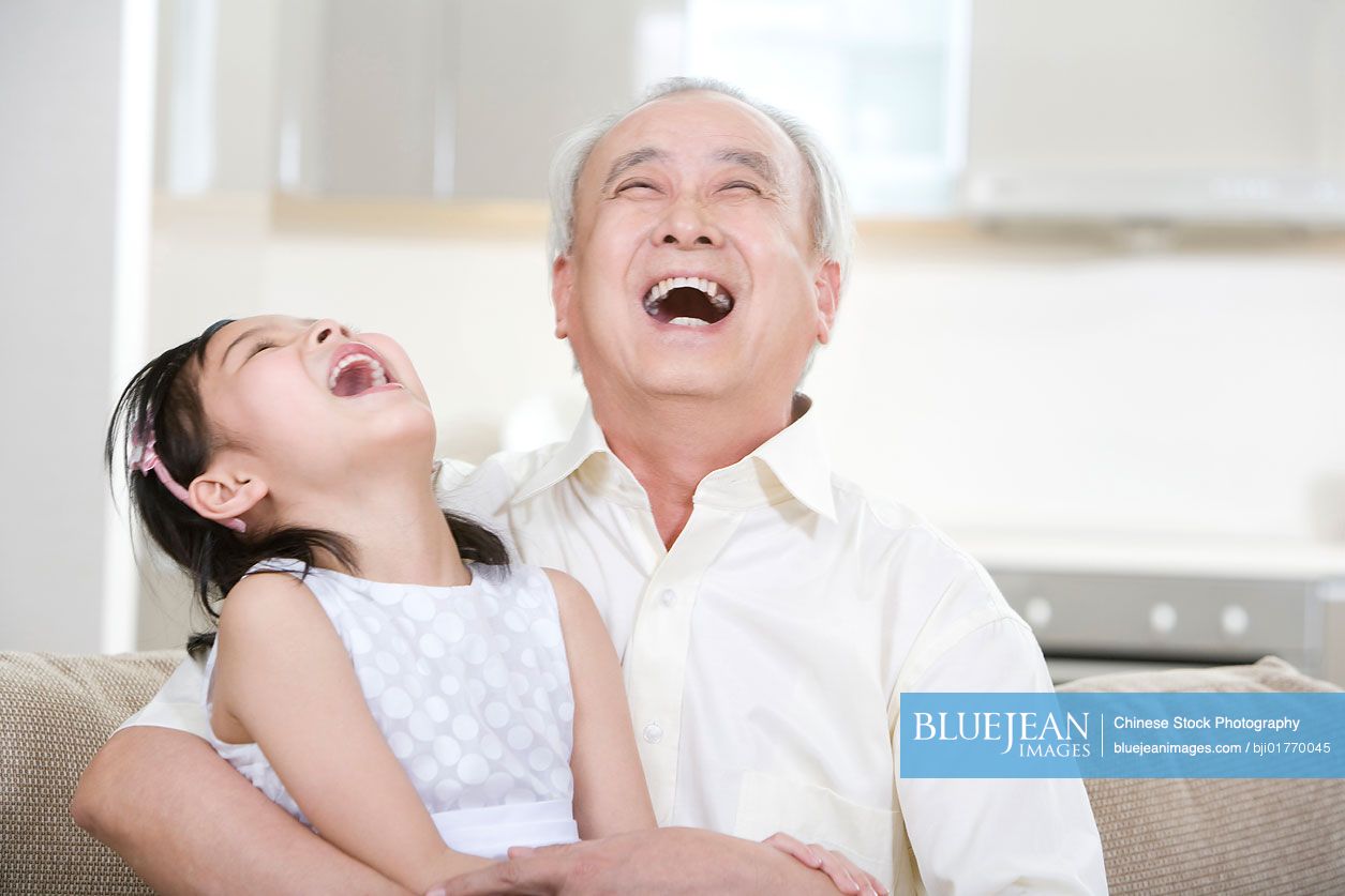 Portrait of Chinese grandfather and granddaughter at home