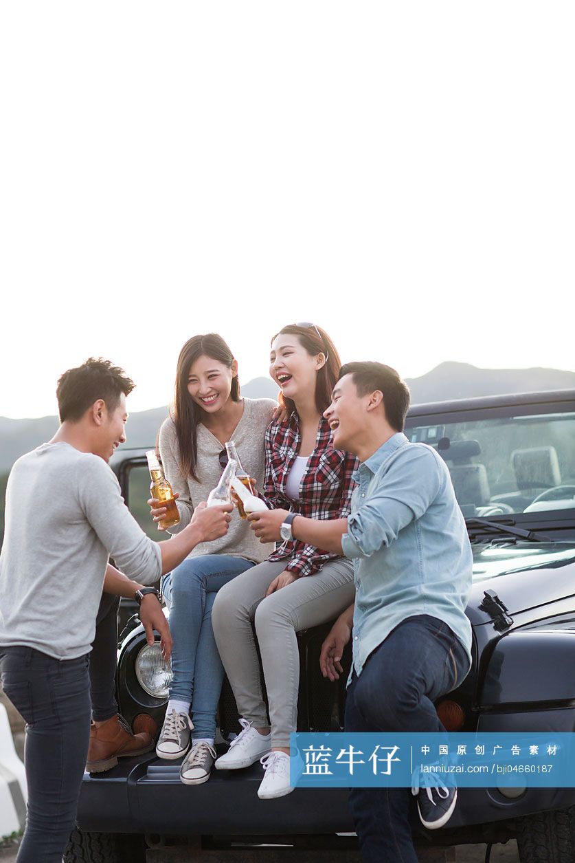 年轻人坐在吉普车上喝啤酒