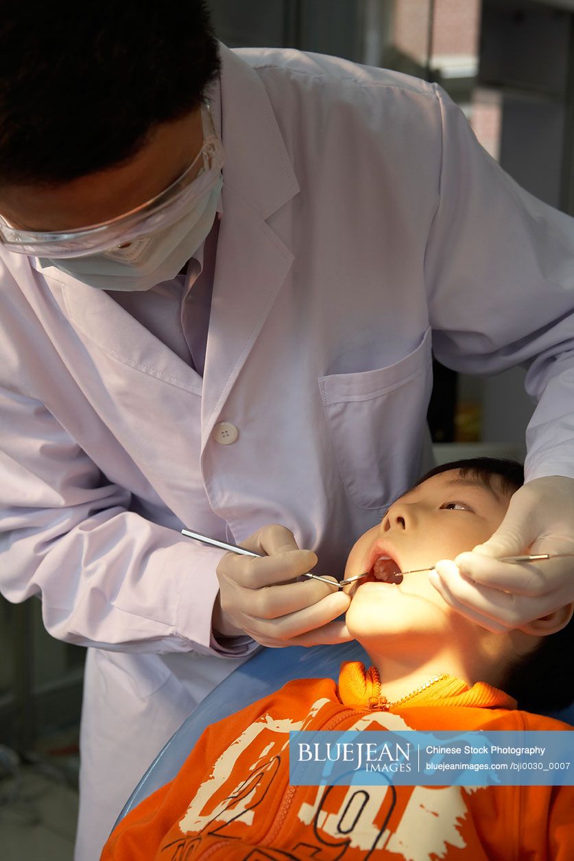 Chinese dentist examining boy's teeth