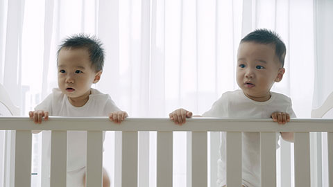 Two twin babies playing in their crib