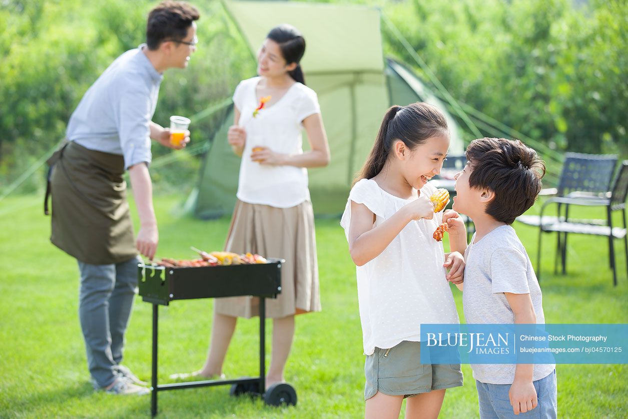 Young Chinese family barbecuing outdoors