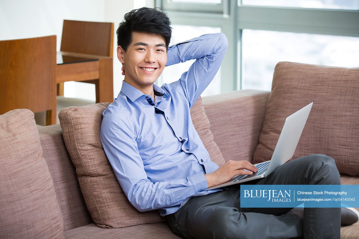 Happy young Chinese man using laptop