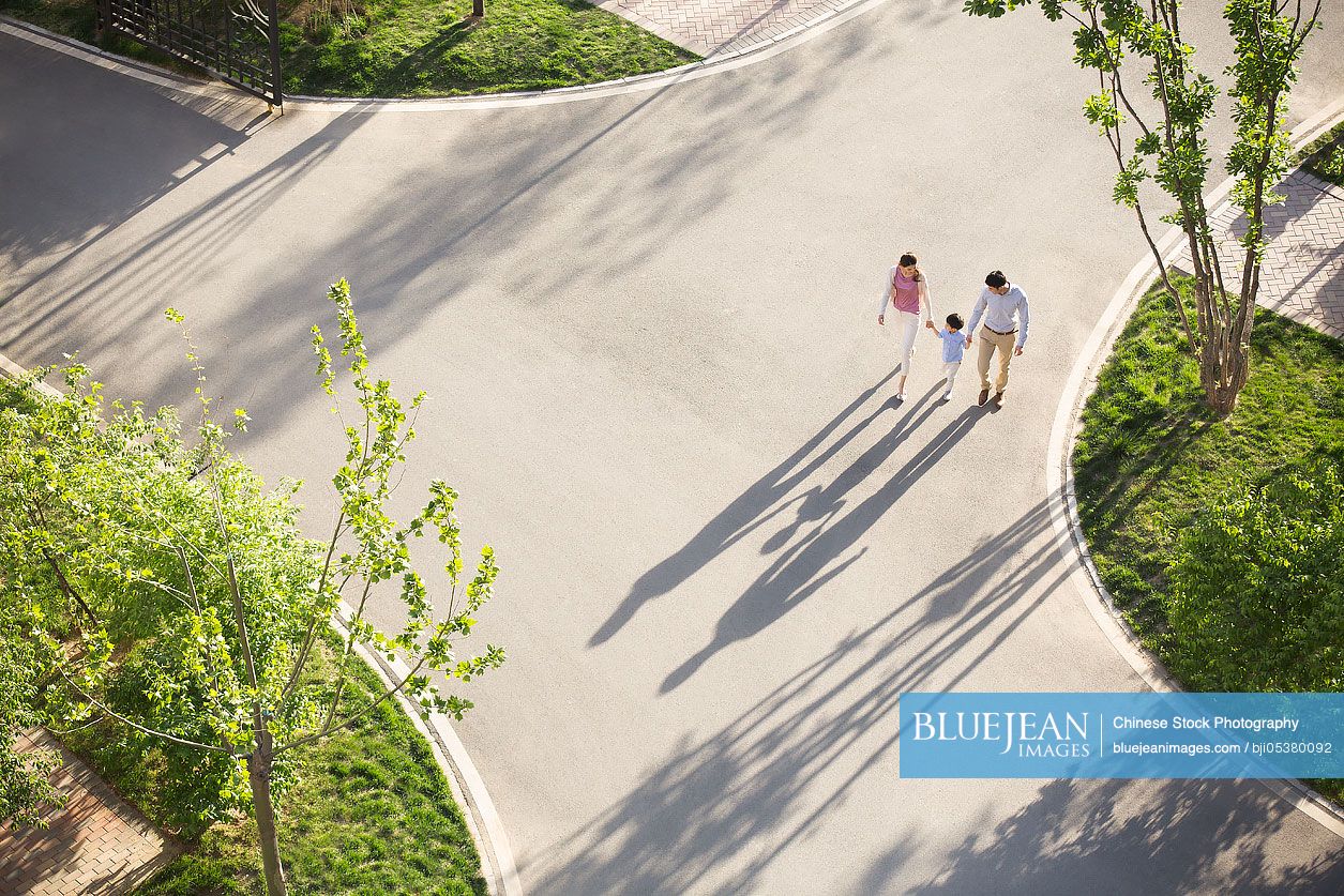 Happy young Chinese family holding hands walking