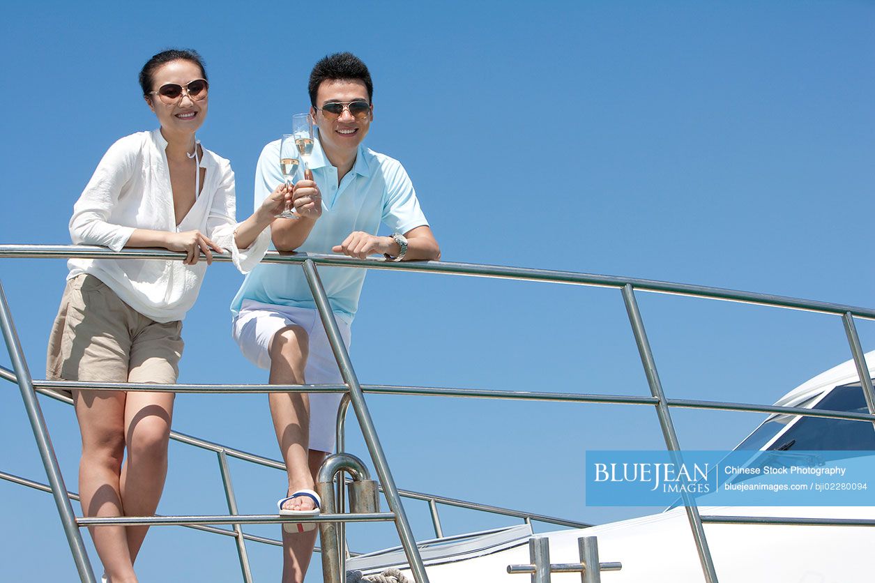 Chinese couple toasting champagne on a yacht